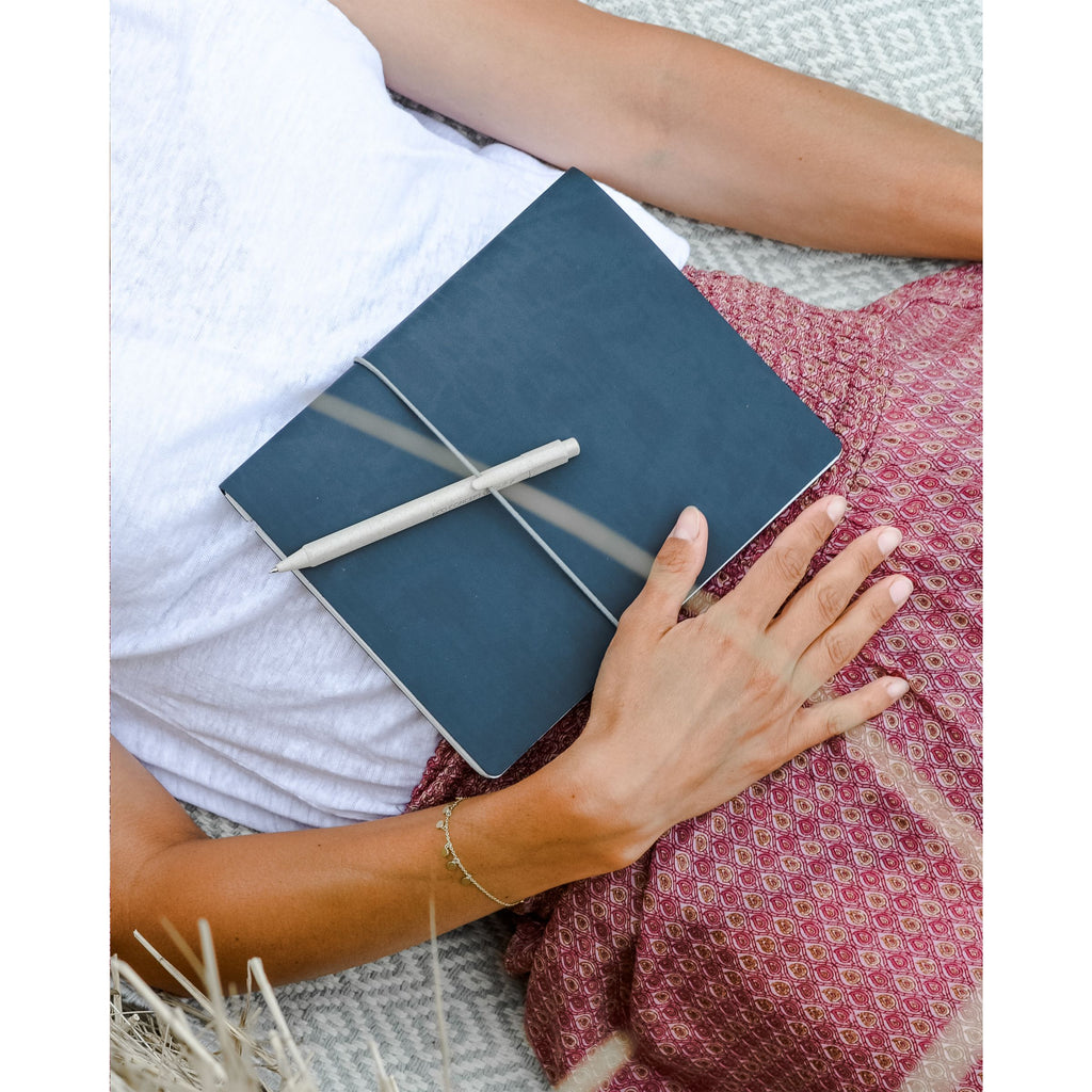 Blaues Notizbuch mit Kugelschreiber als Moodbild mit einer Frau
