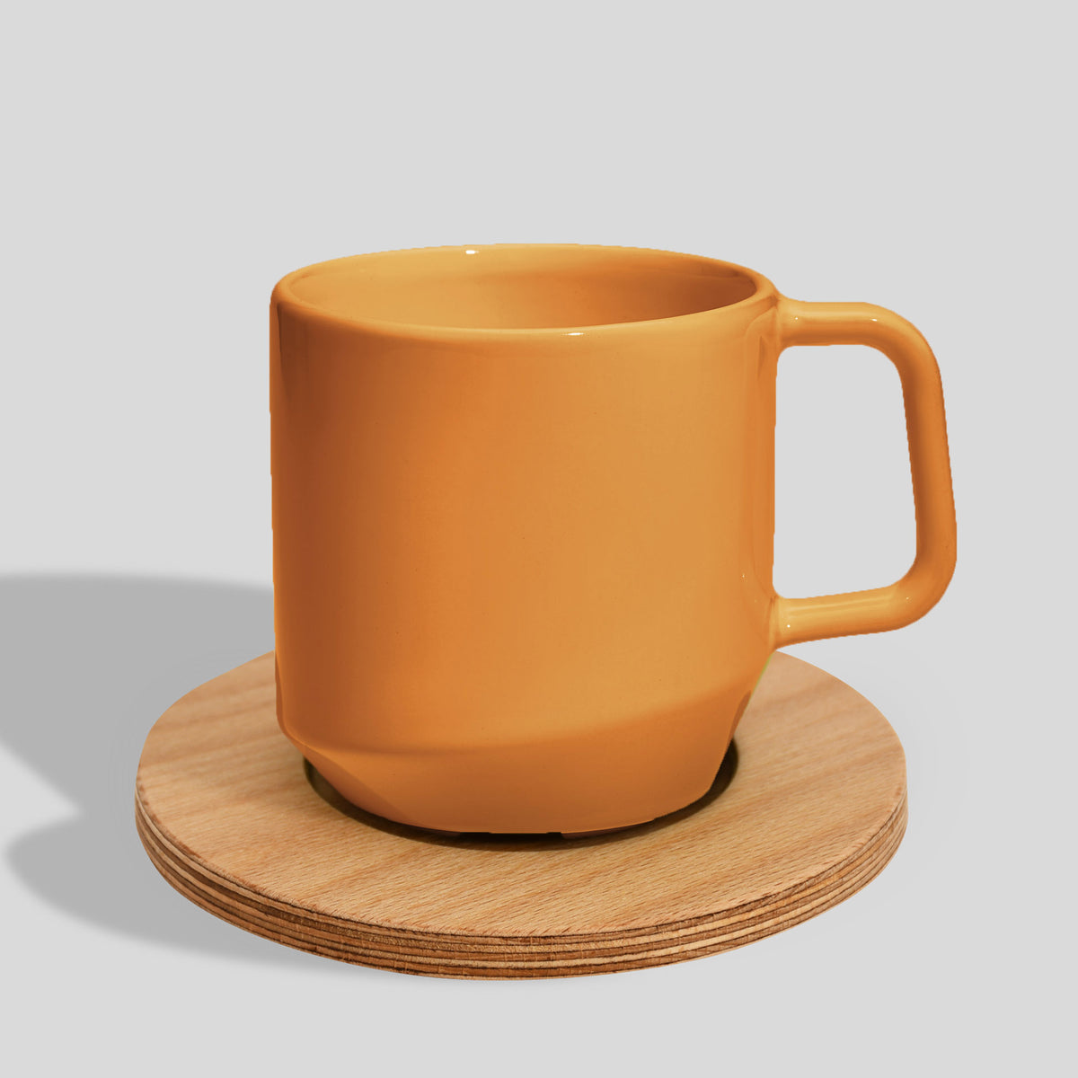 Keramiktasse 400 ml mit Eckhenkel auf Holzuntersetzer – Senfgelb